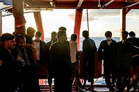 Des migrants à bord du navire « Ocean Viking »  regardent l'horizon, au large du golfe de Catane.
