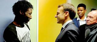   Emmanuel Macron salue un migrant soudanais au centre d’accueil de Croisilles (Pas-de-Calais), le 16 janvier 2018. À ses côtés, Gérard Collomb, alors ministre de l’Intérieur, qui révélera, dans « Le Point » le 13 novembre dernier, avoir démissionné par opposition à l’idée du président de créer des centres de contrôle en France.  ©MICHEL SPINGLER