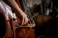 Jeu d'archet sur les cordes d'une contrebasse, une musicienne pratique la musique dans sa chambre.
