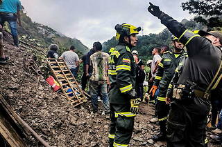 Des dizaines de secouristes sont à la recherche des passagers d'une moto et d'un bus de service public, coincés dans le glissement de terrain.

