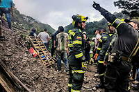 Des dizaines de secouristes sont a la recherche des passagers d'une moto et d'un bus de service public, coinces dans le glissement de terrain.
