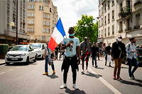 À Paris, le 20 juin 2020, une personne tient un drapeau français lors d'une manifestation pour la régularisation des sans-papiers en France. 

