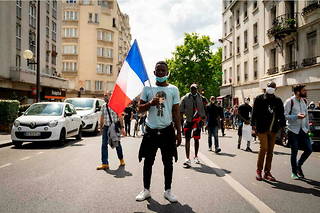 À Paris, le 20 juin 2020, une personne tient un drapeau français lors d'une manifestation pour la régularisation des sans-papiers en France. 
