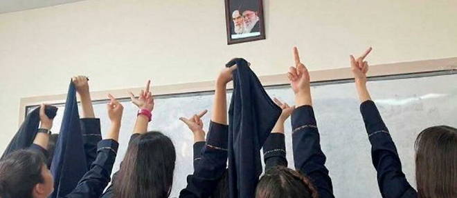 Des ecolieres iraniennes poitent leur majeur en direction des portraits des ayatollahs Khomeyni et Khamenei, les deux guides supremes successifs de la Republique islamique d'Iran. 
