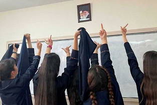 Des écolières iraniennes poitent leur majeur en direction des portraits des ayatollahs Khomeyni et Khamenei, les deux guides suprêmes successifs de la République islamique d'Iran. 
