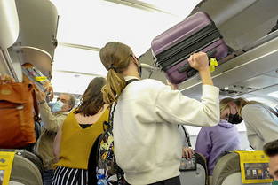 Les passagers rangent les bagages cabine dans les coffres prévus à cet effet.
