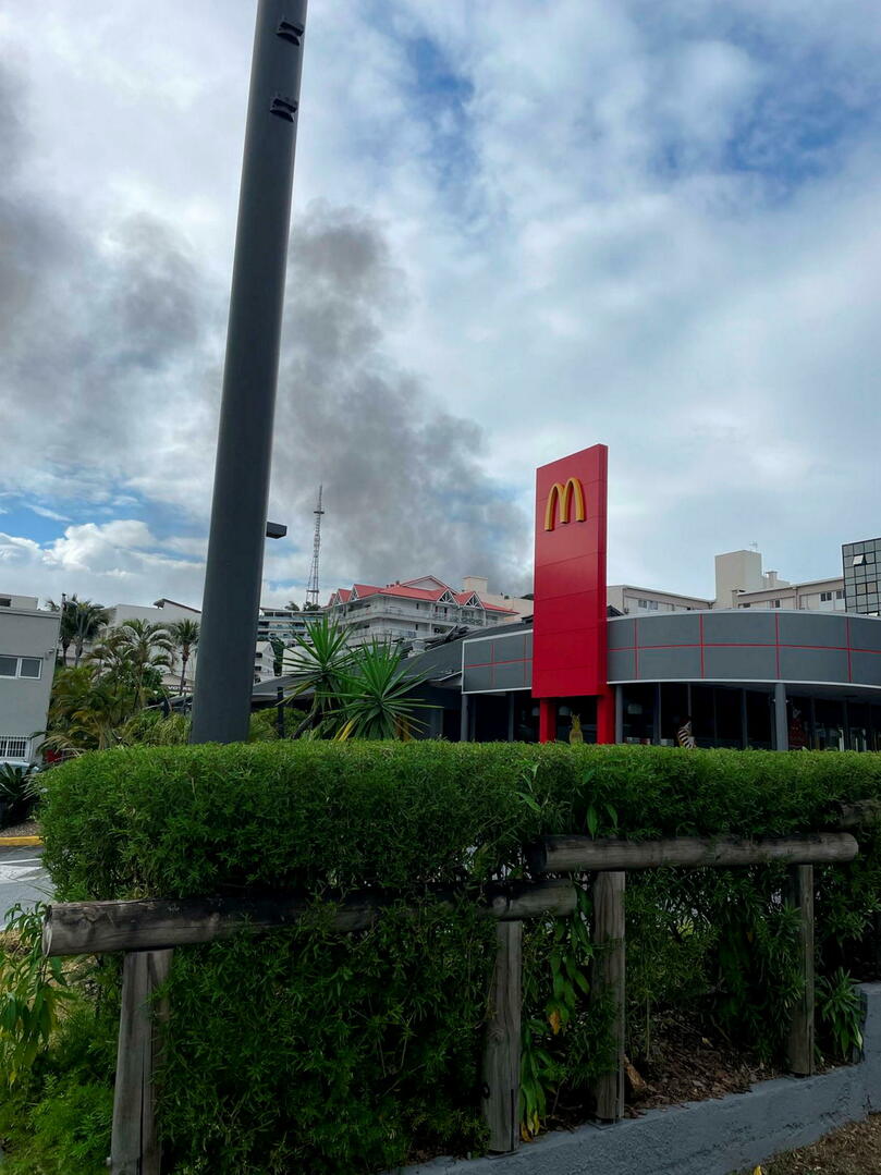 Au Quartier latin à Nouméa, le McDonald fermé, avec au loin une colonne de fumée provenant d'affrontements.
©  Gabriel Page
